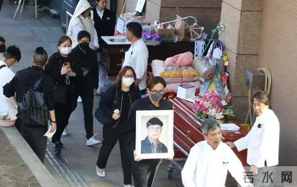 马国明父亲出殡。他手捧遗照神情哀伤，妻子汤洛雯陪伴左右