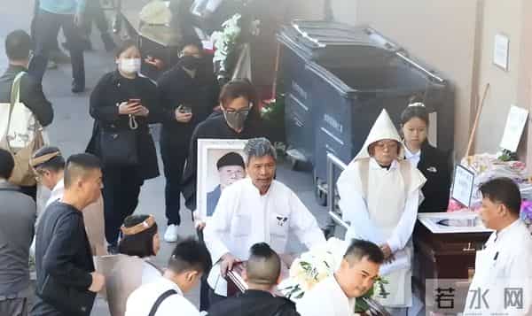 马国明父亲出殡。他手捧遗照神情哀伤，妻子汤洛雯陪伴左右