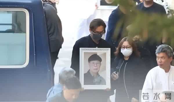 马国明父亲出殡。他手捧遗照神情哀伤，妻子汤洛雯陪伴左右